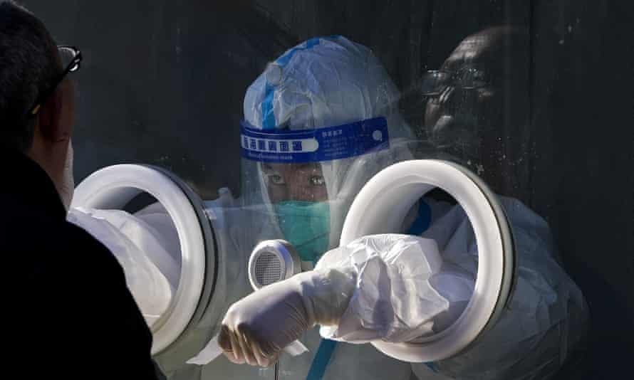 A medical worker in protective gear collects a sample from a resident at a coronavirus test site in Xichen District in Beijing, 25 January. Hong Kong has already suspended many overseas flights and requires arrivals be quarantined, similar to mainland China’s “zero-tolerance” approach to the virus that has placed millions under lockdowns and mandates mask wearing, rigorous case tracing and mass testing.