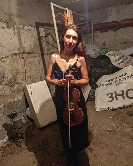 Violinist Vera Lytovchenko in a formal dress, holding her violin, in her cellar