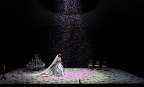 A woman in a wedding dress walks across a stage covered in confetti