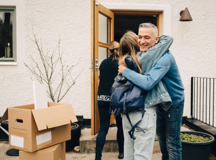 A father hugs his daughter while standing in the back yard next to cardboard boxes