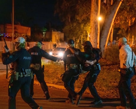 A woman is carried by police officers