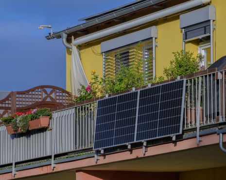 Upper floor of a yellow building with a solar panel installed on the outside of a metal balcony.