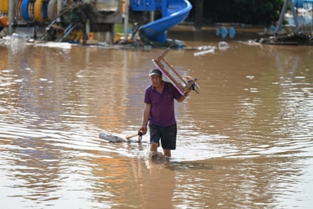 A resident carrying a table walks through a flooded area in Miyun district.
