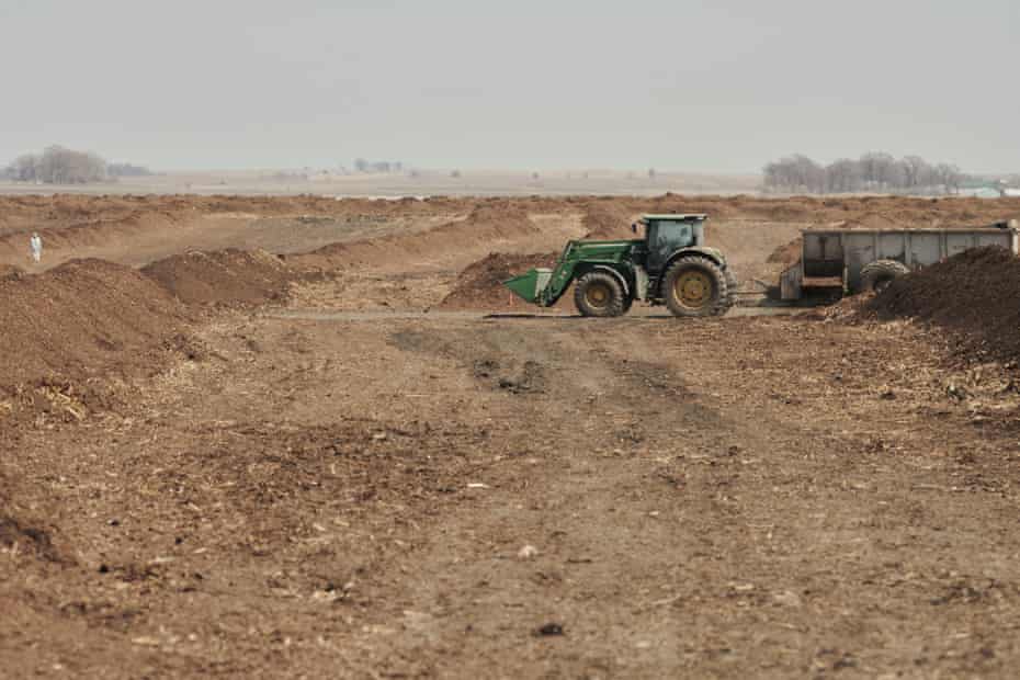 A green tractor in a field of dirt piles