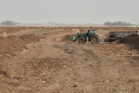 A green tractor in a field of dirt piles