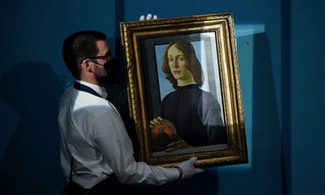 A worker at Sotheby's auctions hangs Sandro Botticelli's Young Man Holding a Roundel.