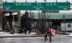 People walk with Canadian flags as truckers and supporters continue blocking access to the Ambassador Bridge, which connects Detroit and Windsor, in protest against Covid mandates