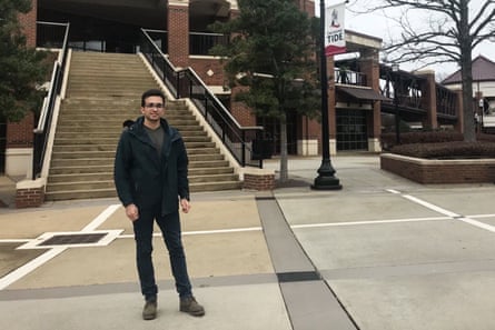 person wearing black jacket and pants stands in front of building