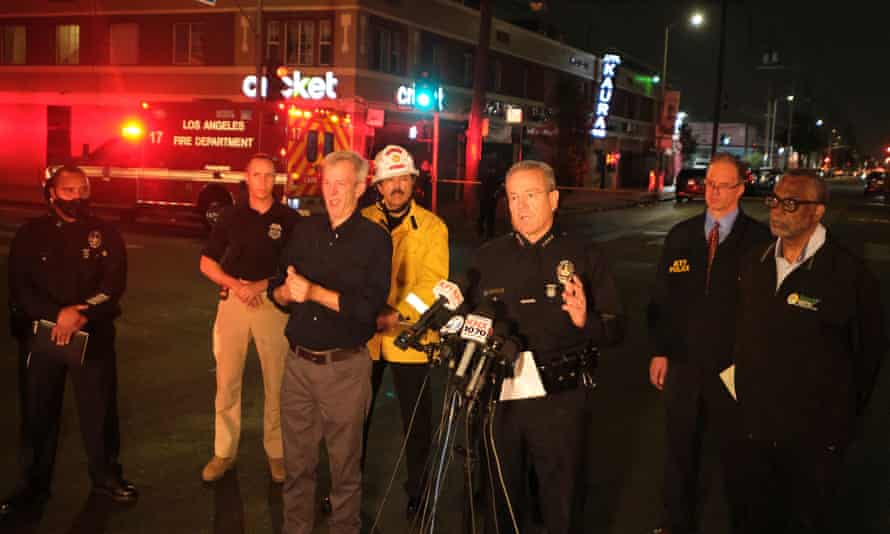 Michel Moore, center, talks to the media after illegal fireworks seized at a South Los Angeles home exploded.