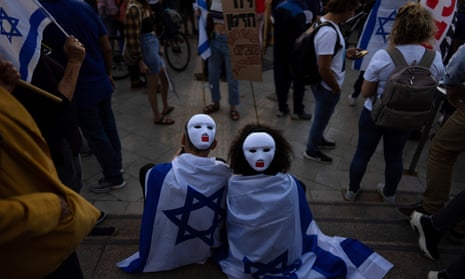 Demonstrators wear masks and wrapped in Israeli flags during a protest against plans by Prime Minister Benjamin Netanyahu's government to overhaul the judicial system in Tel Aviv, Israel, Tuesday, March 28, 2023. Netanyahu said Monday he was freezing the plan to give time to seek a compromise with his opponents, but protesters have vowed to continue their demonstrations, saying they don't trust him. (AP Photo/Oded Balilty)