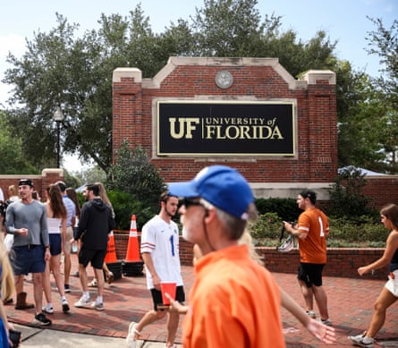 people walking by a sign for the University of Florida