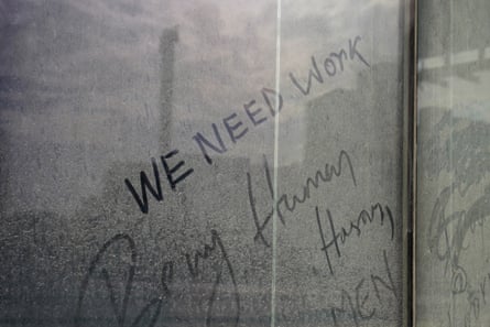 Una ventana sucia con las palabras "Necesitamos trabajo" escritas en polvo