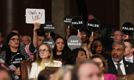 Democrats hold protest signs as Donald Trump address a joint session of Congress.