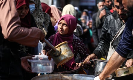 Displaced Palestinians wait to receive food