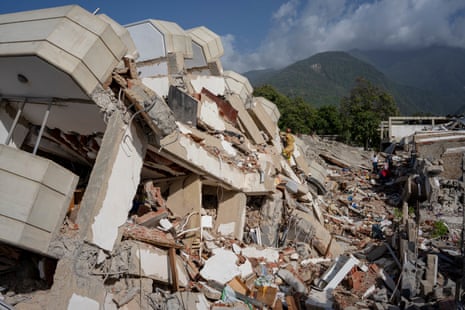 A Brazilian firefighter scales a collapsed building in La Guaira.