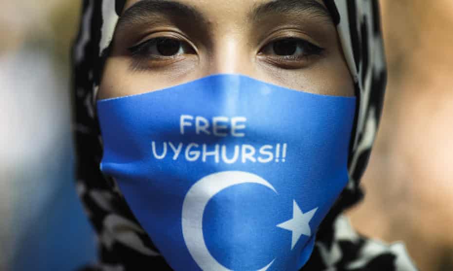 A protester wears a mask highlighting human rights abuses in China’s Xinjiang region