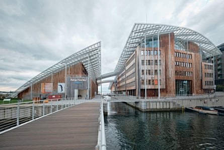 A modern wood and glass building with a curved metal roof, split in two by a canal.