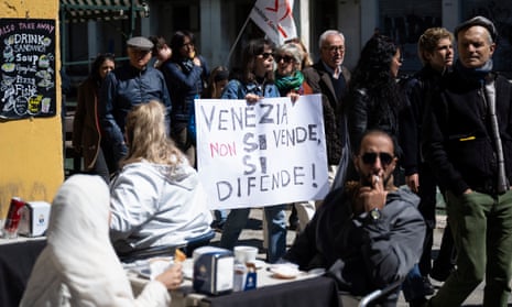 A woman holds a banner reading "Venice is not sold, it is defended" as protestors take part in a demonstration.