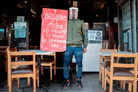 The manager of a restaurant in Parkhurst, Johannesburg, holds a banner during a national protest against the lockdown.