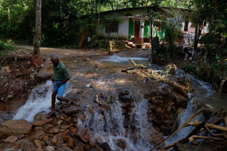 A landslide survivor crosses a section of a damaged road in Sarasavigama village in Kandy.