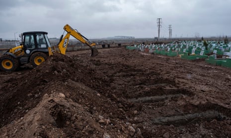 An excavator digs graves for victims of the earthquake at a cemetery in Diyarbakir, southeastern Turkey.