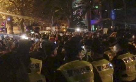 Police, foreground, watch protesters in Shanghai on Saturday, in an image from video