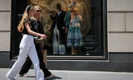 Two women walk past a shop window on 5th Avenue