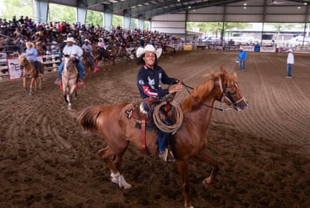 A man in a cowboy hat rides a horse in an arena