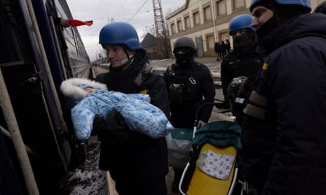 A member of Ukraine's emergency service passes a baby to their mother aboard an evacuation train in Pokrovsk, Ukraine, after an increase of Russian missile strikes on settlements in the area around Avdiivka, amid Russia’s attack on Ukraine, February 20, 2024.