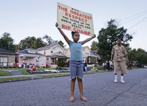 Akera Price-King, 9, carries a sign saluting Muhammad Ali on the street in front of his boyhood home