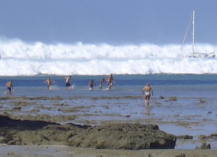 Tourists are seen far beyond the beach as tsunamis loom behind them