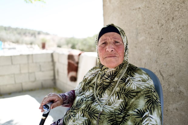 An old woman sitting on a terrace looks at the camera
