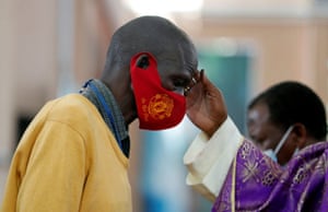 Cardinal John Njue marks a cross on the forehead of a man during mass at the Cathedral Basilica of the Holy Family in Nairobi, Kenya