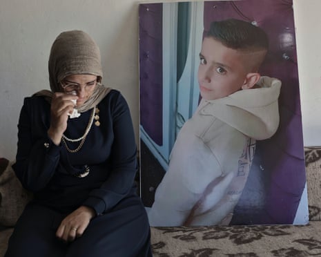 Aliyah al-Halaq dabbing her eye on a sofa next to a poster-sized photo of Muhammad looking over his shoulder to the camera