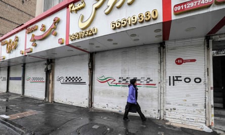 A woman walks past closed shops along Satarkhan street in Iran’s capital Tehran