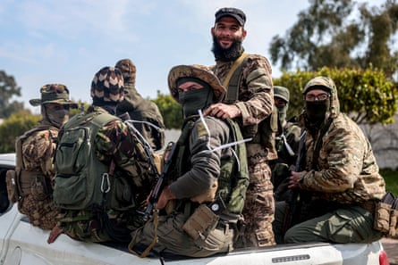 Security forces loyal to the interim Syrian government ride in the back of a vehicle in Latakia, 9 March 2025.