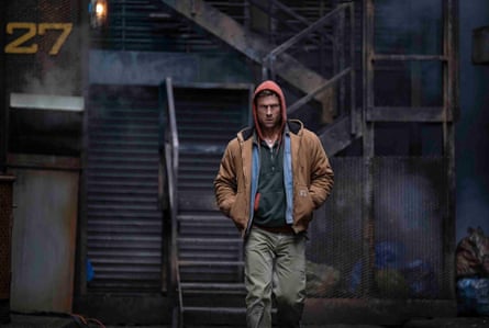 A still from The Running Man of Glen Powell, who plays Ben Richards, in casual clothing walking towards the camera with his hand in his jacket pockets
