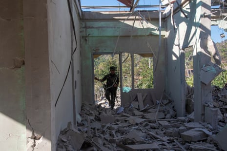 A worker walks done a bombed retired building pinch nary tile and missing walls.