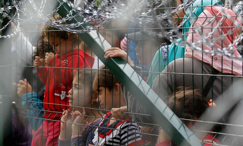 Refugees stand behind the fence in Serbia at the closed border with Hungary.