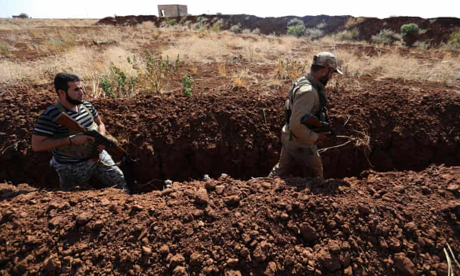 Syrian rebel fighters walk in a newly dug trench in the village of al-Zakat in the northern countryside of Hama province on 17 September.
