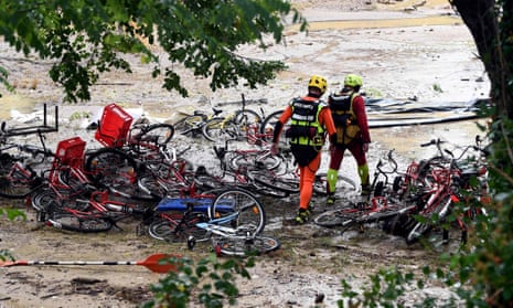 Rescuers walk past damaged bicycles at a flood-hit campsite
