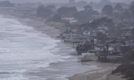 waves creep close to houses lining a beach on a grey day