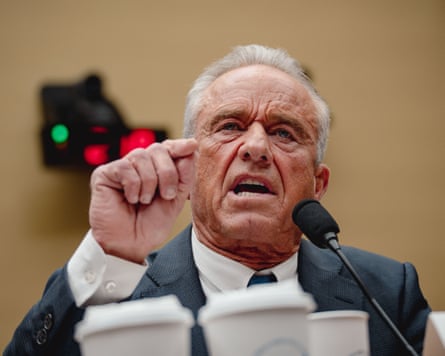 Man sits at microphone and points with mouth open