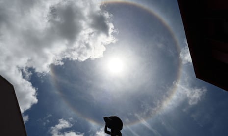 A halo forms around the sun above a statue in Singapore. The halo is formed when light from the sun or moon passes through ice crystals suspended in the upper atmosphere. 
