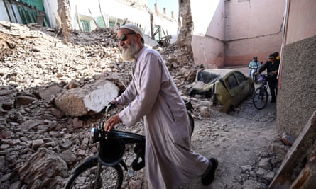 People walk through collapsed buildings in Marrakech