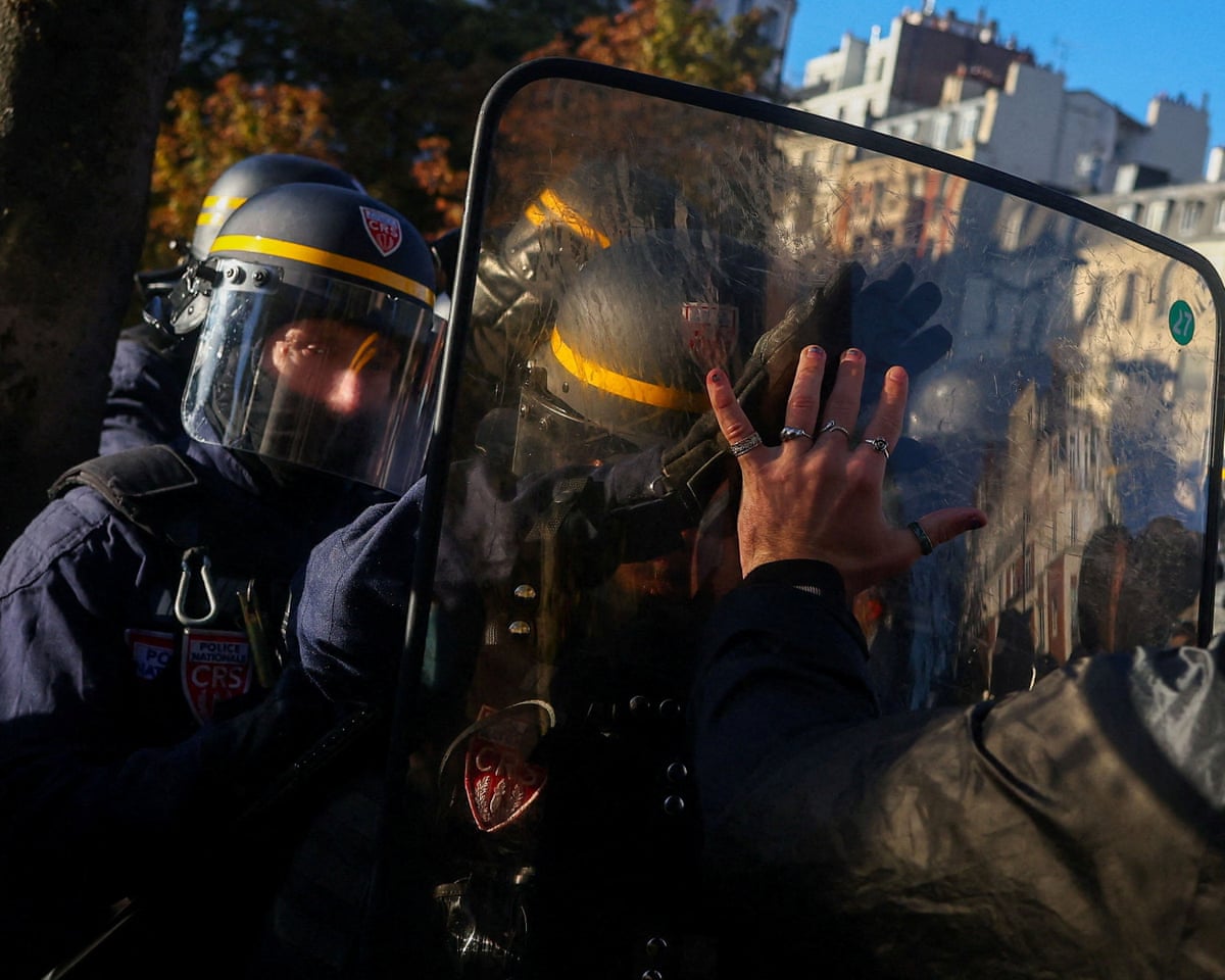 A protester confronts riot police officers outside Lycee Helene-Boucher high school as students block the road, during nationwide protests in Paris, France.