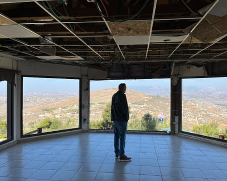 An Israeli resident looks out over Lebanon from a damaged building