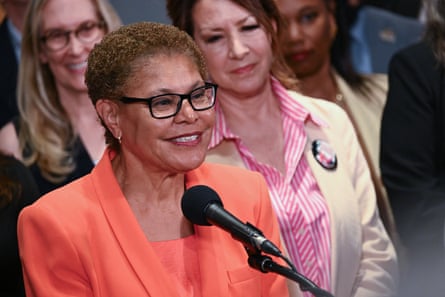 a woman in coral suit smiles while standing behind a microphone