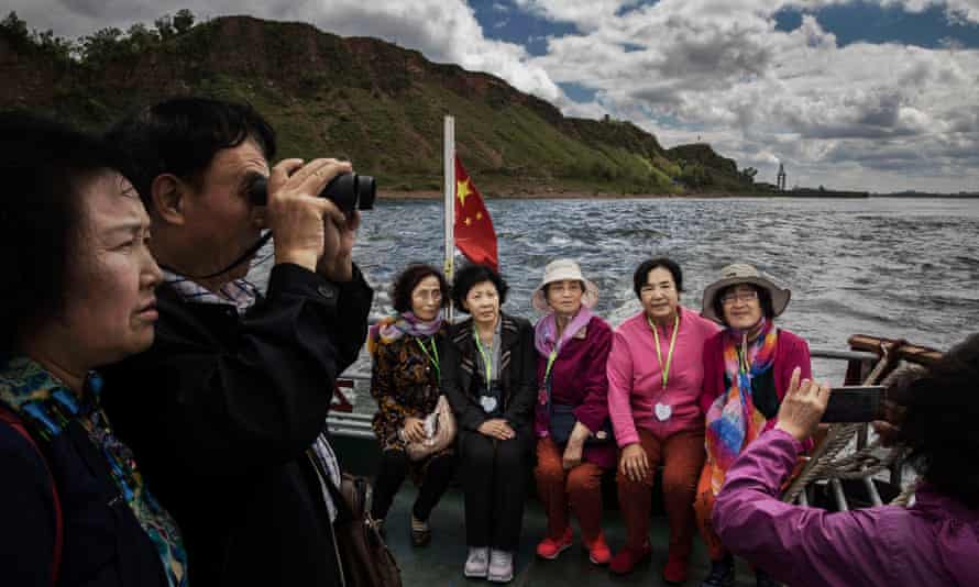 Chinese tourists ride in a boat on the Yalu river with North Korean territory on both sides north of the border city of Dandong.