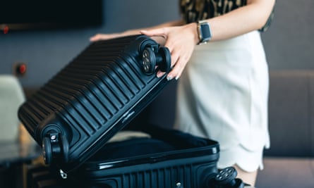 A woman closes a black, hard-sided suitcase.